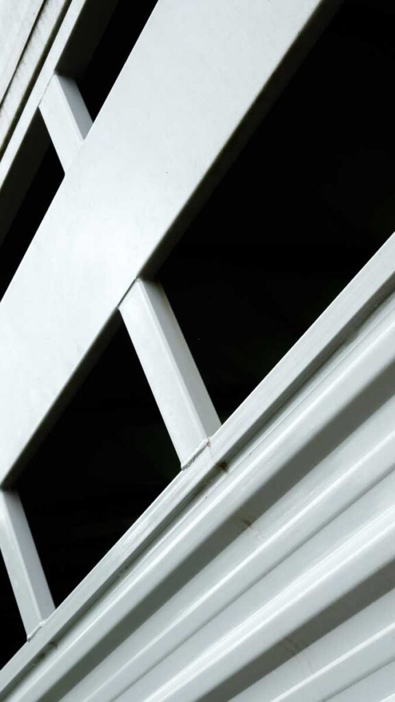 Abstract close up of a horse trailer. The open windows form dark spaces within lighter gray lines.